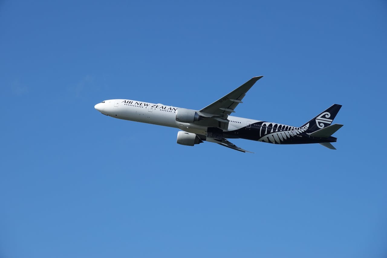 An Air New Zealand airplane flying against a clear blue sky, showcasing aviation elegance.