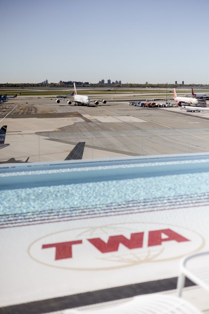 Airplanes parked on the tarmac at New York Citys airport with TWA branding in view.