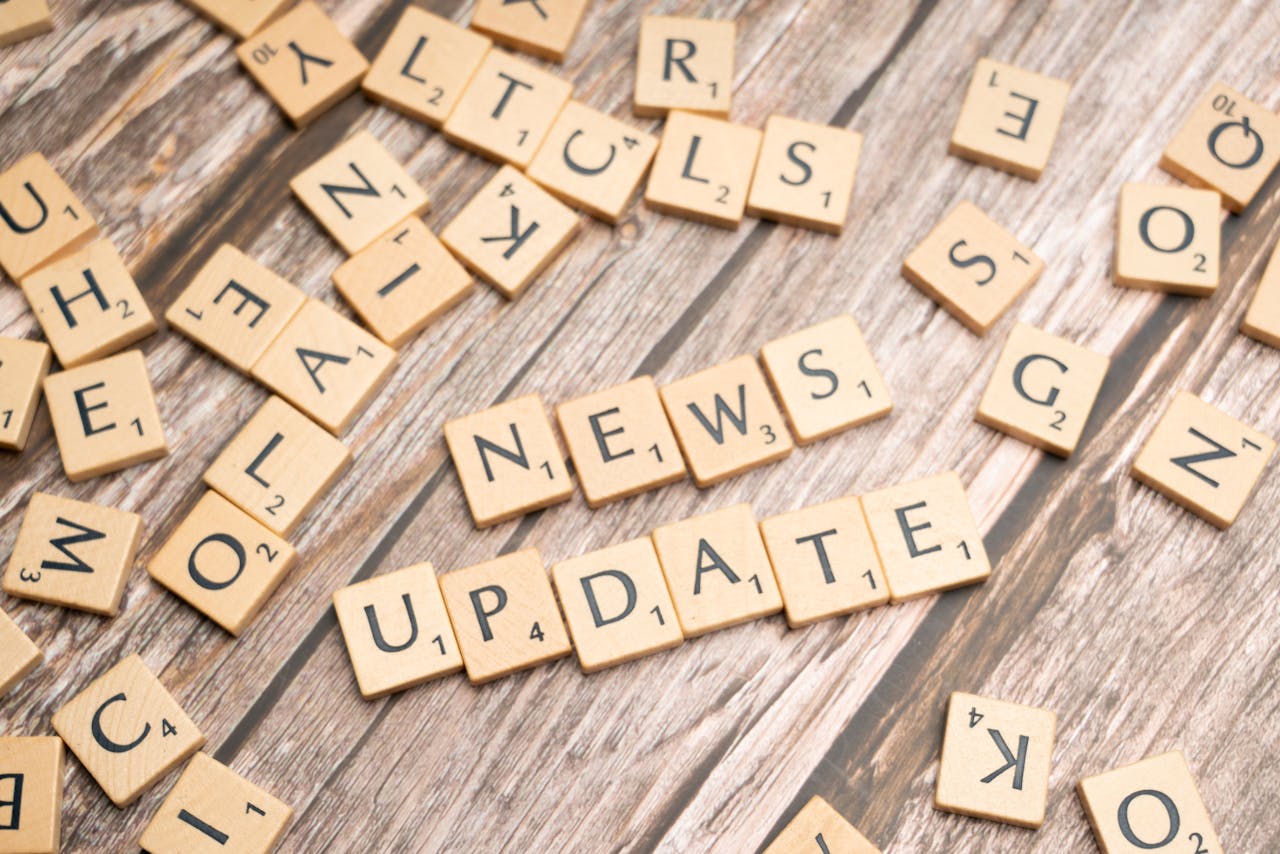 Scrabble tiles spelling News Update on a wooden background, ideal for media and communication concepts.
