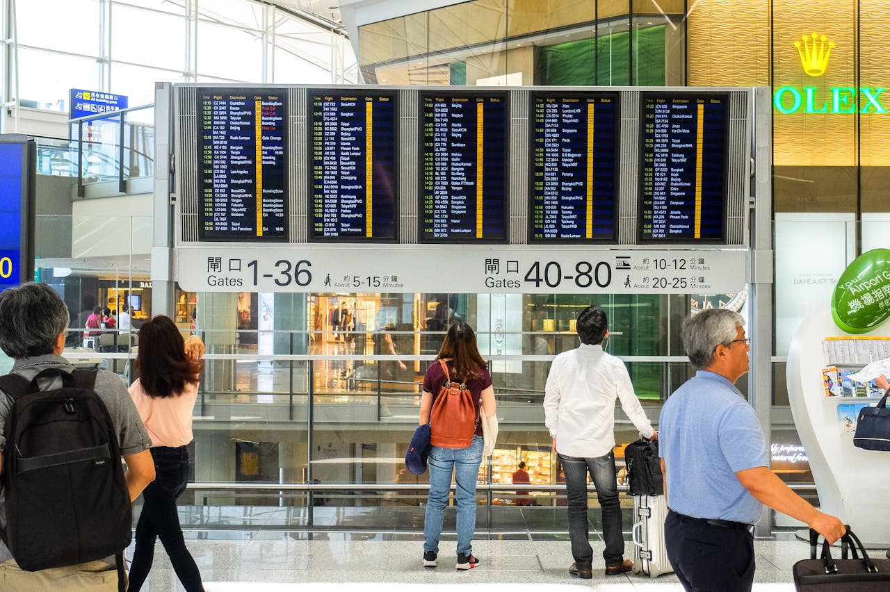 Passengers checking the departure board at Hong Kong International Airport terminal.